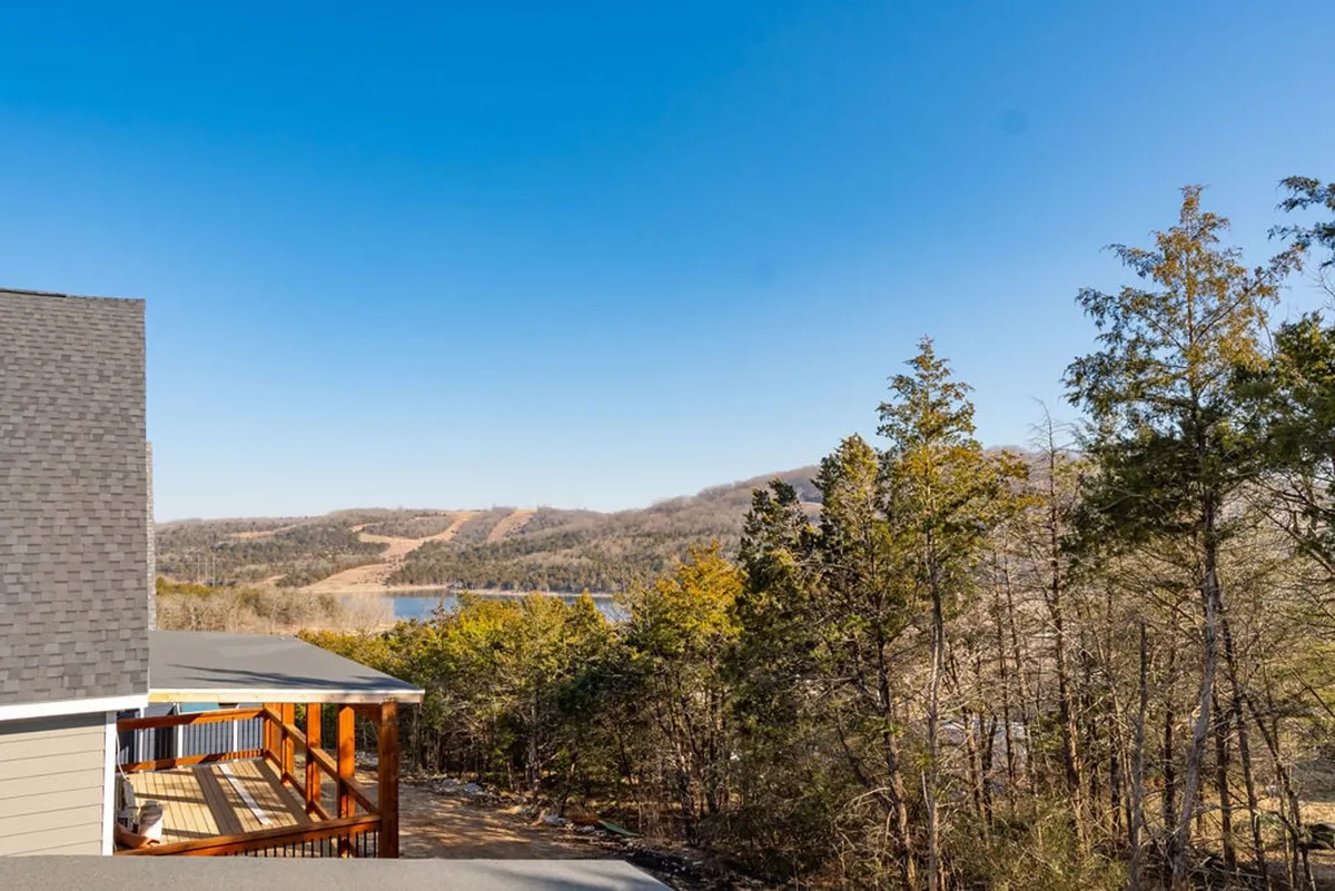 A tranquil view over Table Rock Lake, framed by wooded areas and rolling hills in the background. The perspective suggests the serenity guests can experience from the deck, perhaps while enjoying morning coffee or soaking in sunset views.