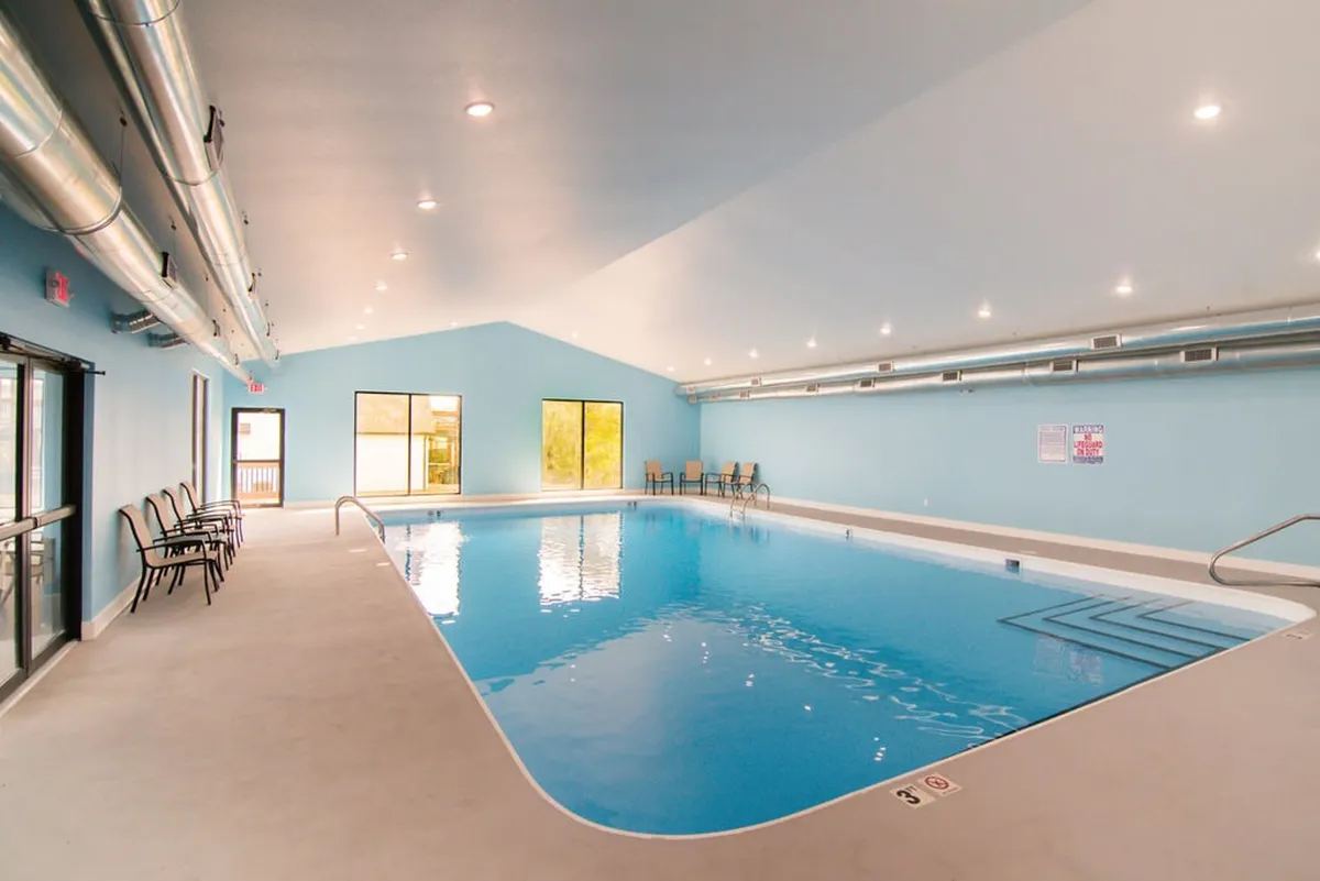 An inviting indoor swimming pool with large windows that fill the space with natural light. Comfortable seating areas surround the pool, offering a relaxing, spa-like environment perfect for year-round enjoyment.